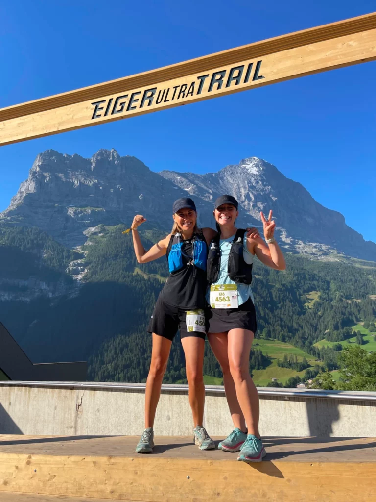 Darien and a friend stand in front of the Eiger Ultra trail, with beautiful mountains in the background