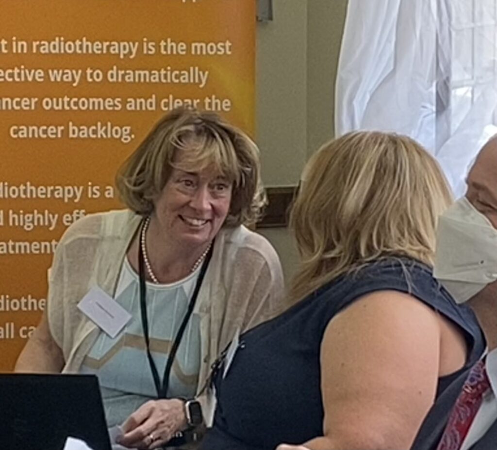 Prof Pat Price talks engagingly with attendees at the special radiotherapy event at Westminster on June 14th. She smiles, and has mid-length highlighted hair and a beige and white top