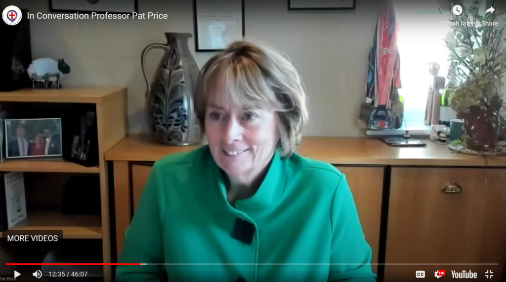 Prof. Pat Price wears a smart green jacket and smiles at the camera from her study. She has a brown highlighted bob