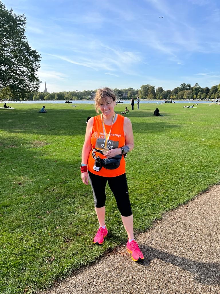 Professor Pat Price at Royal Parks Half marathon, wearing a bright orange #Miles4Radiotherapy vest and smiling