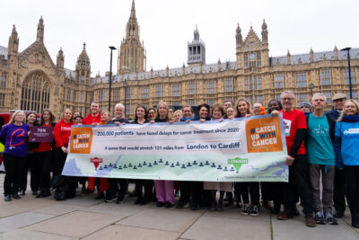 Campaigners outside parliament for last year's World Cancer Day, holding a large banner.