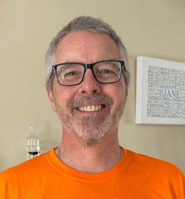 Andy smiles at the camera, wearing his bright orange Radiotherapy UK T-shirt